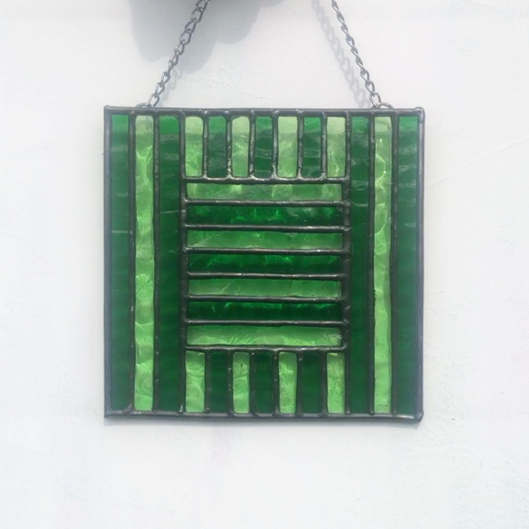 pale and deep green glass stripes are shaped to form a green glass square. Set against white background, no light shines through