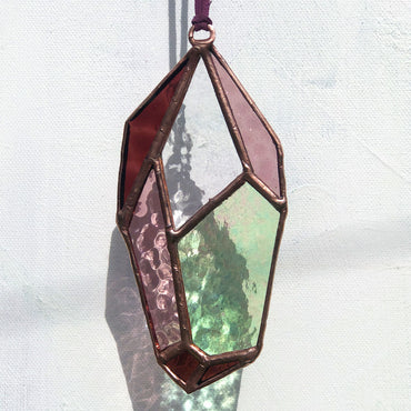 Purple and clear crystal suncatcher with copper patina against a white background