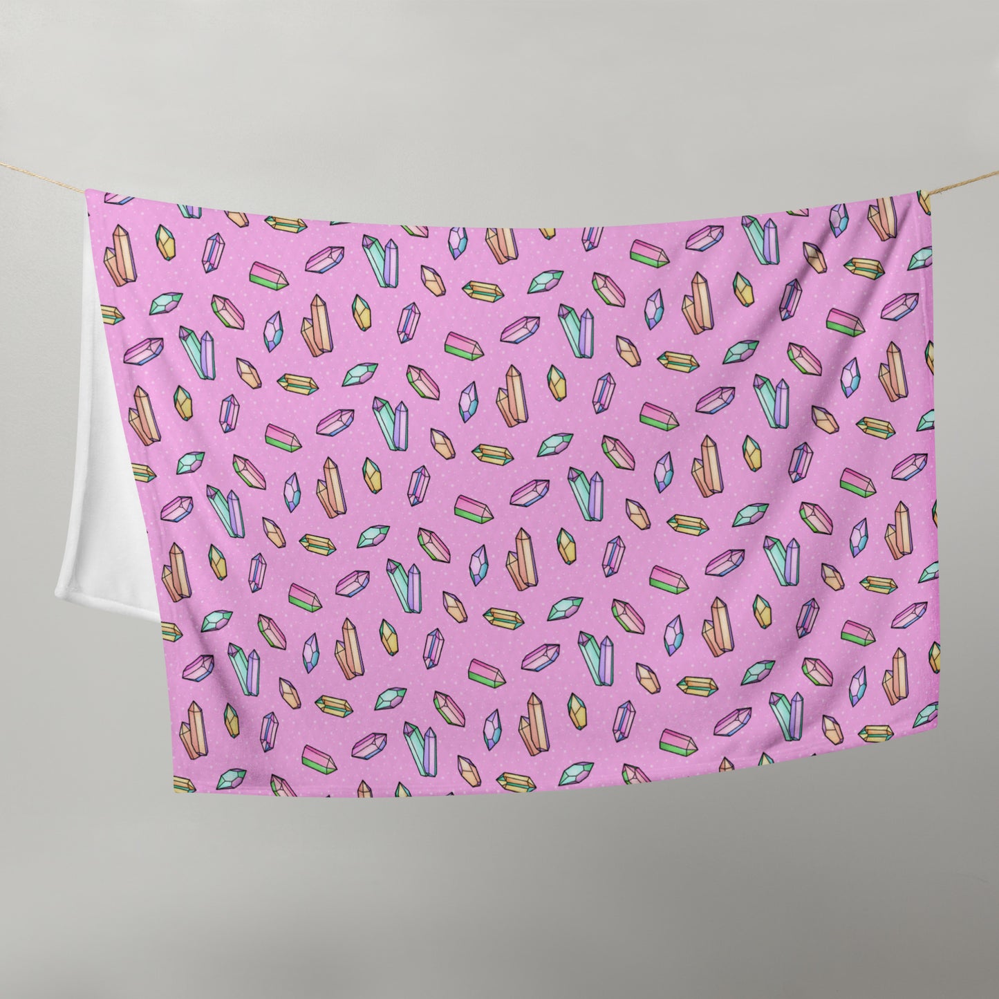 image of 50" x 60" blanket hanging in half on a clothes line to show size with repeated pattern image of rainbow crystals on a pink background