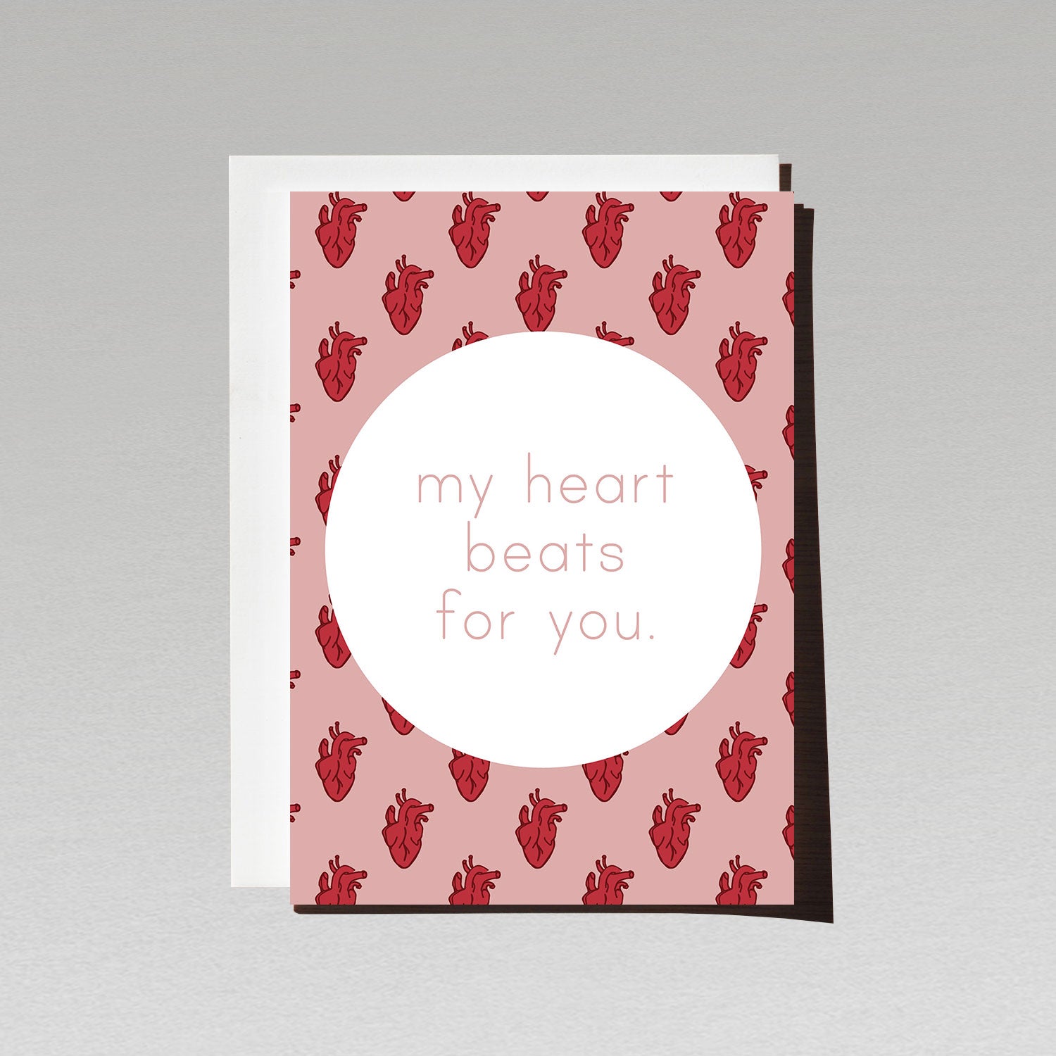 Greeting card with red anatomical hearts on pink background with text My heart beats for you